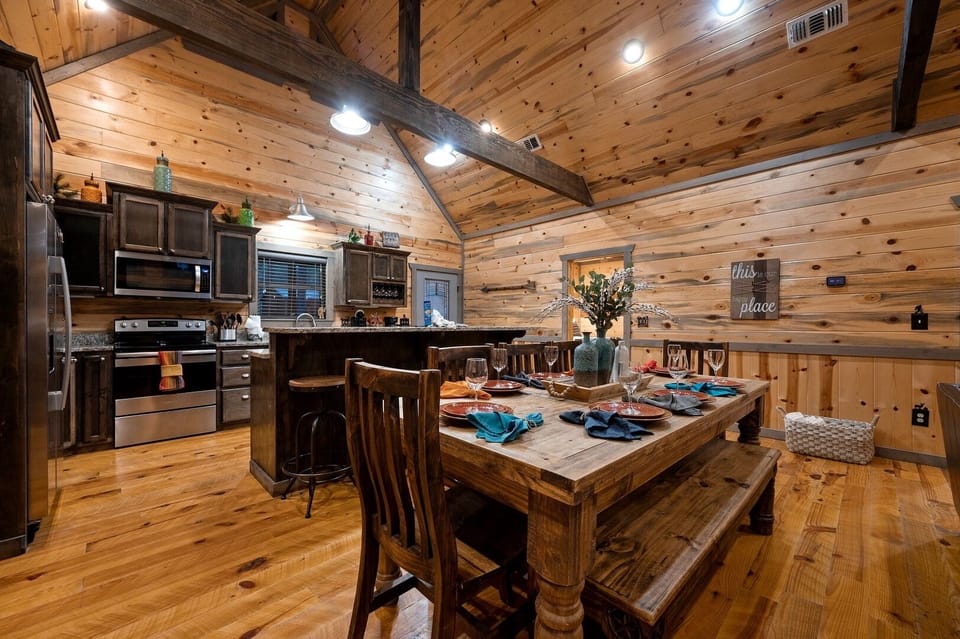 Gather around your rustic dining table where warm wood surrounds you in this cozy cabin kitchen perfect for memorable meals together.