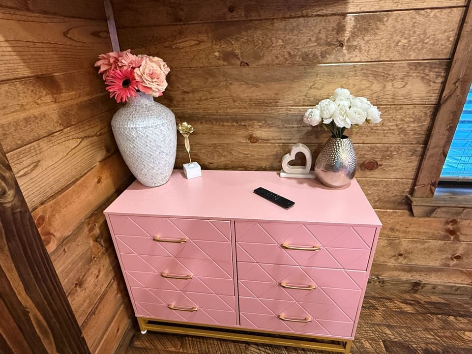 Store your belongings in this charming pink dresser, styled with fresh flowers and rustic wood walls to make your stay feel warm and welcoming.