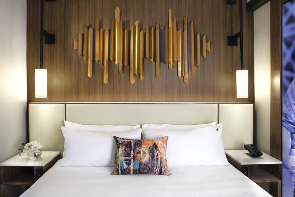 Sink into crisp linens beneath striking modern headboard art.