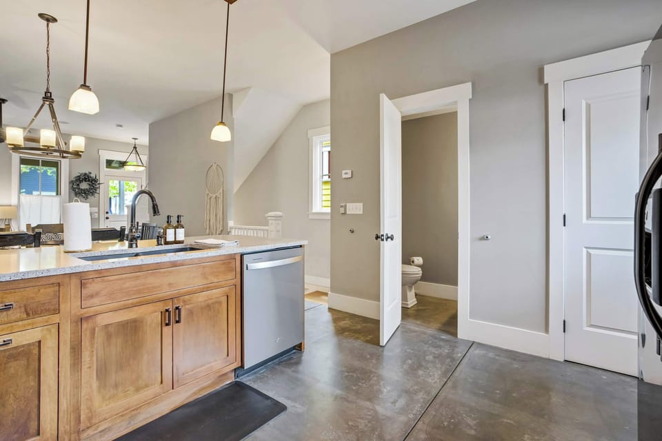 The kitchen sink area offers a practical and well-appointed workspace, with light stone countertops, warm wood cabinetry, and a dishwasher tucked neatly beneath, keeping everything within easy reach during meal prep.