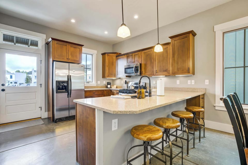 The warm glow of the gold-tone chandelier draws you into the dining space, where a handwoven wall piece adds mountain character and the kitchen flows naturally just beyond, keeping the whole main level connected.
