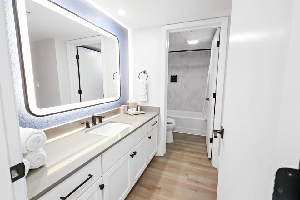 Refresh under glowing mirror light in a spotless bath.