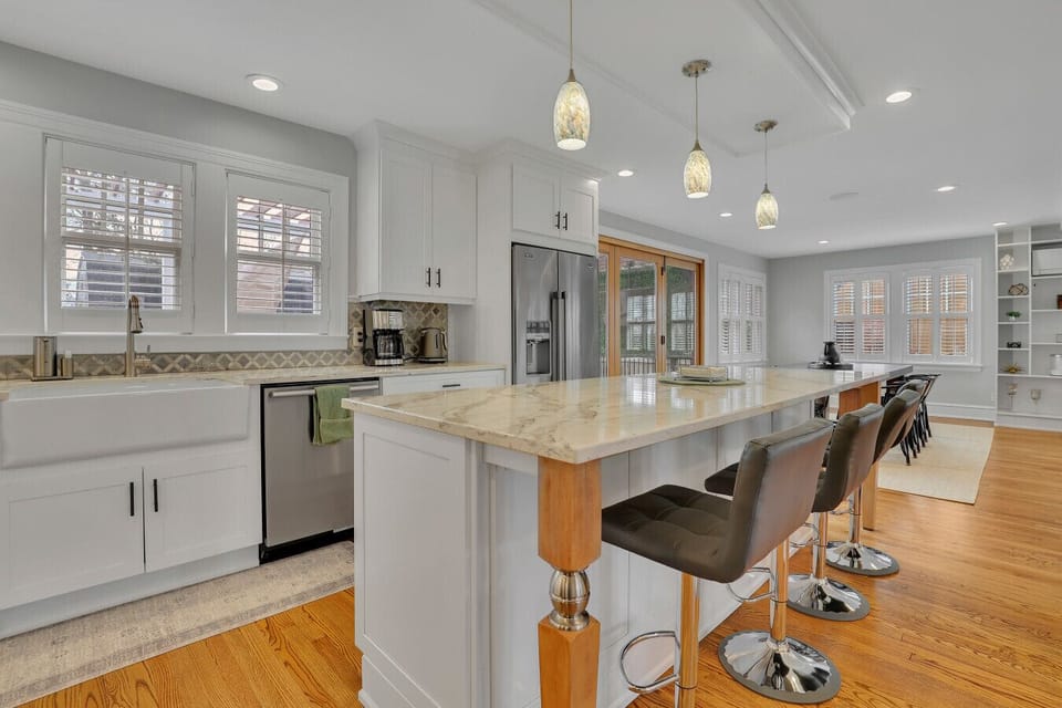Spacious kitchen with seating for up to 12 guests, including island seating for 4 and dining for 8, plus a stainless steel side-by-side refrigerator with water and ice dispenser