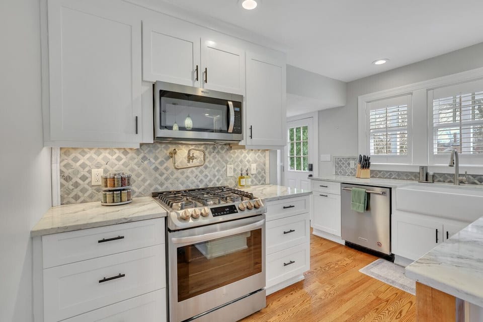Beautiful kitchen featuring a gas range, pot filler, microwave hood, and custom backsplash tile