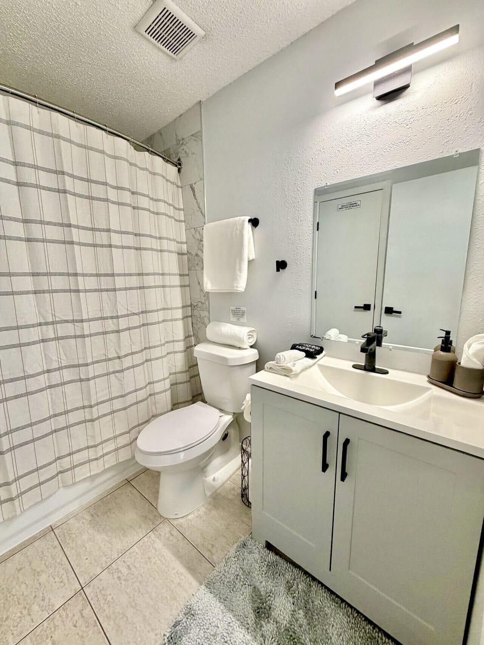 Clean, modern ensuite bathroom with fresh towels and a full tub/shower combo