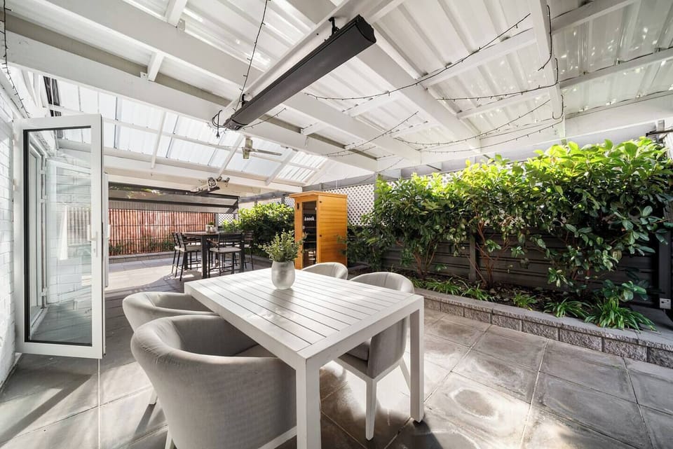 Dine under the covered courtyard, where a spacious dining setting, outdoor heaters, and ceiling fan create a relaxed space for long outdoor meals.