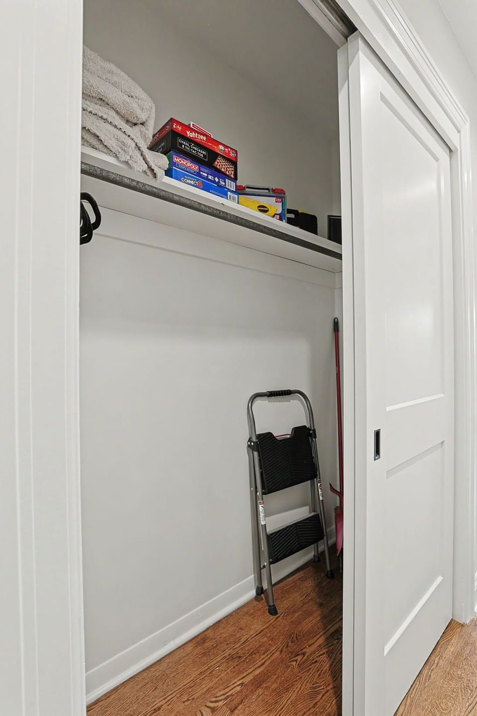 Stocked hall closet with board games, fresh towels, and step stool.