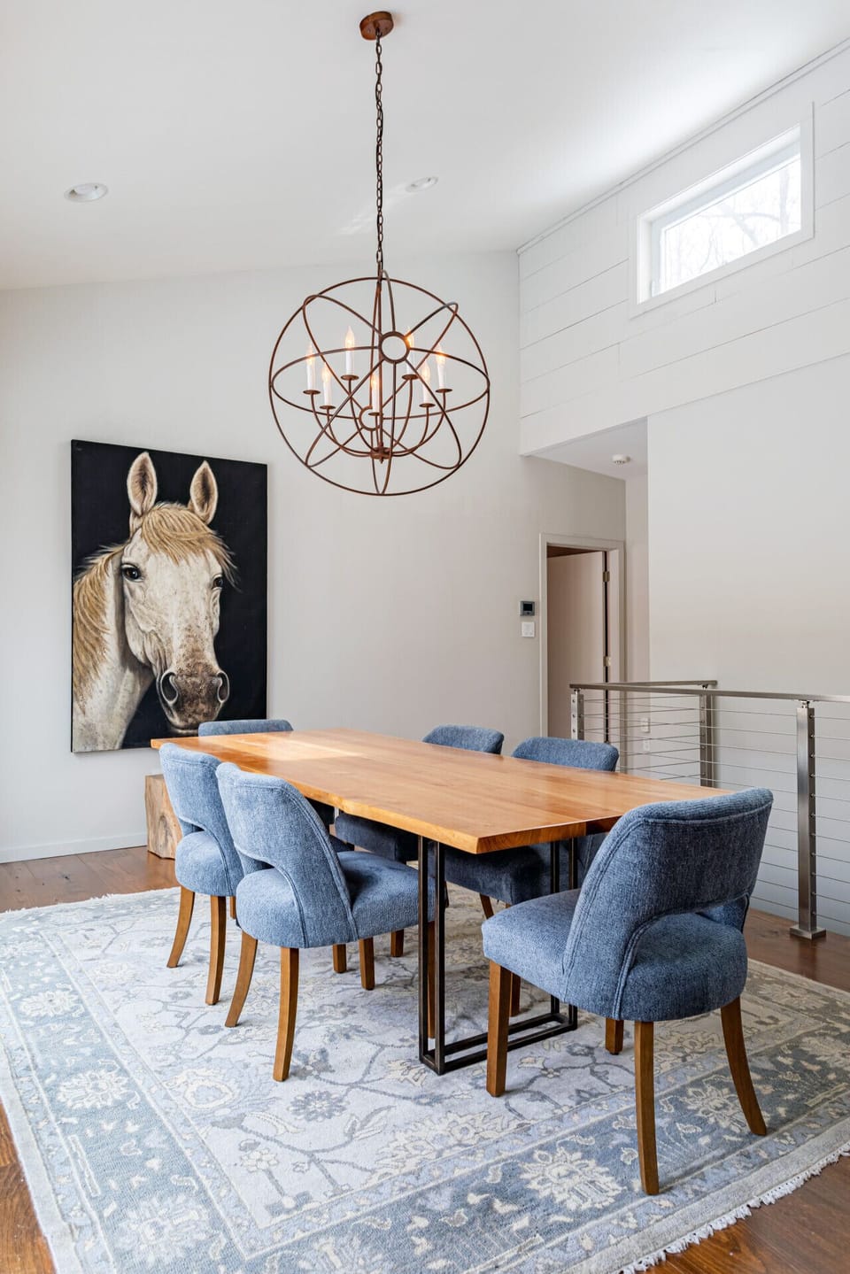 Gather around this dining space featuring a modern chandelier and handcrafted wooden table -perfect for memorable meals together