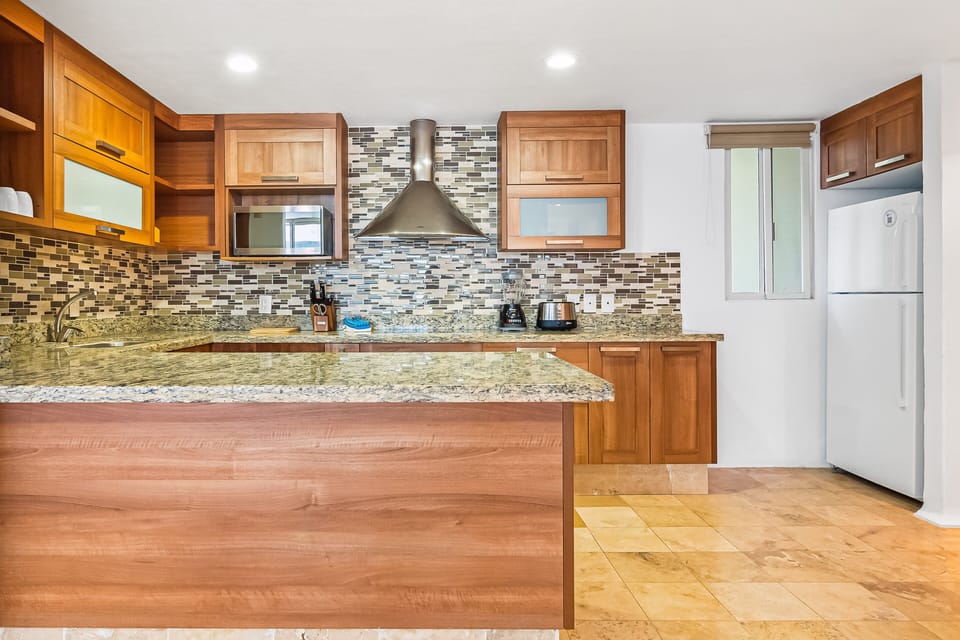 Cook effortlessly in a fully equipped kitchen featuring granite countertops, premium appliances, custom wood cabinetry, and ample prep space.