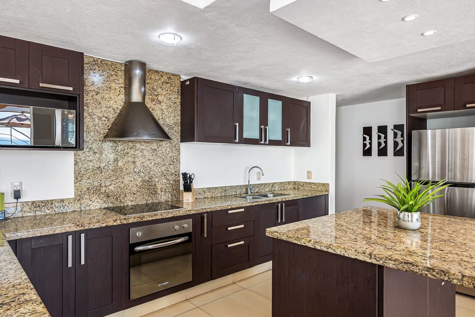 Sleek and spacious kitchen with granite countertops, stainless steel appliances, and a large island perfect for prepping or gathering.