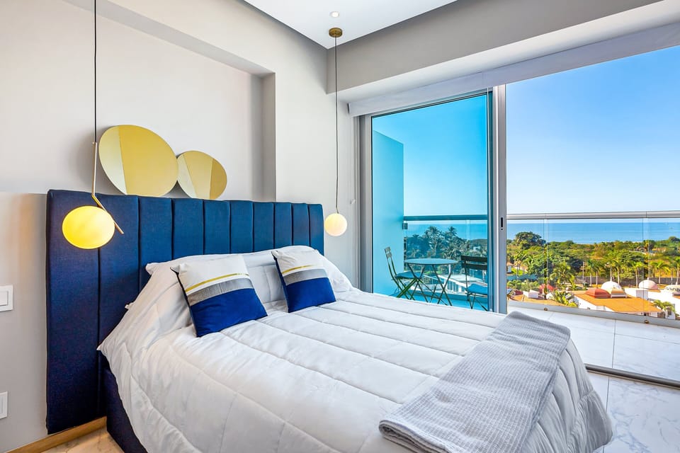Bright and inviting bedroom featuring a plush bed, floor-to-ceiling windows, and beautiful ocean views for a relaxing stay.