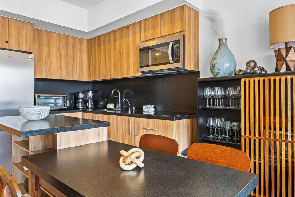 Stylish open-plan living area featuring a custom kitchenette, mid-century modern dining, and a cozy lounge adorned with bold, contemporary art. Perfect for a chic and comfortable coastal getaway.