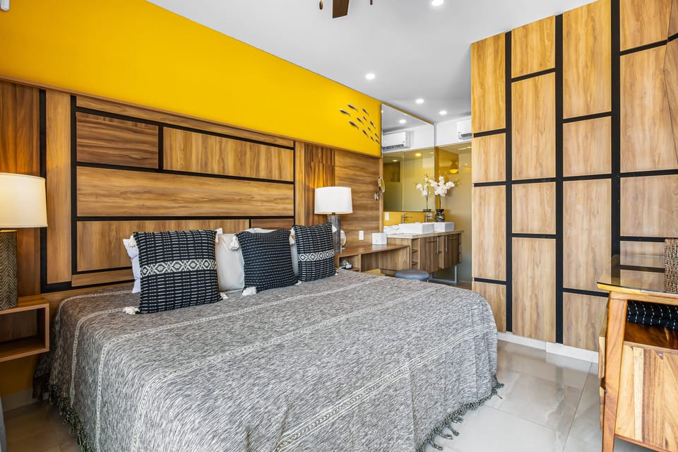 Unwind in this beautifully designed bedroom featuring a plush king-size bed, custom wood paneling, and a warm, inviting color palette. A sleek Smart TV and private sliding door offer the perfect blend of luxury and privacy.