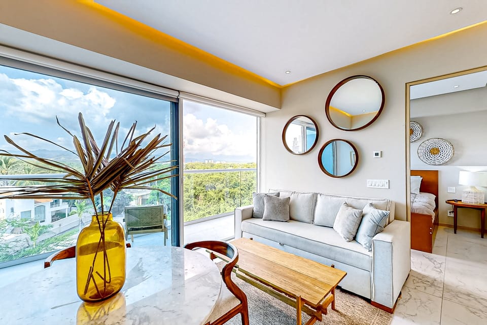 Bright and inviting living space with floor-to-ceiling windows, modern décor, and beautiful tropical views—perfect for relaxing after a day in paradise.
