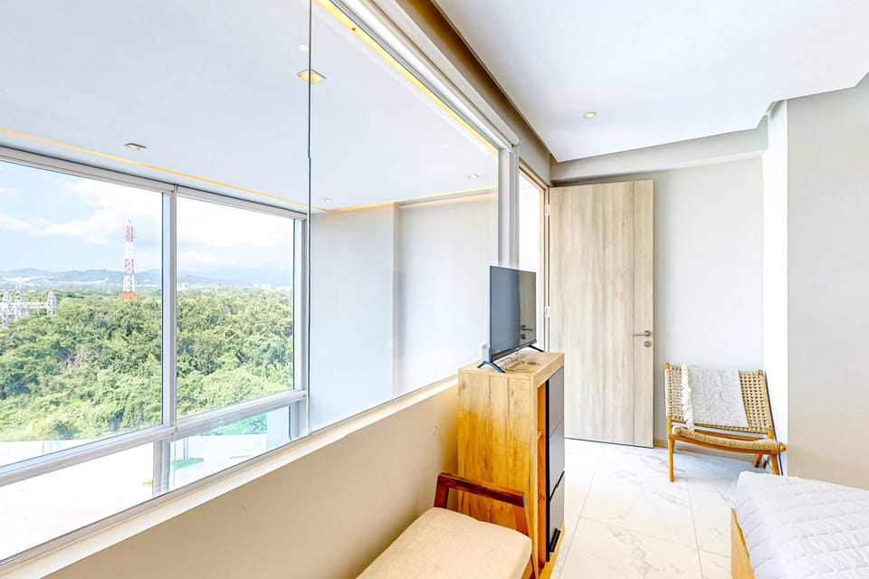 Large windows fill the bedroom with natural light while offering beautiful views of the lush surroundings and golf course area.