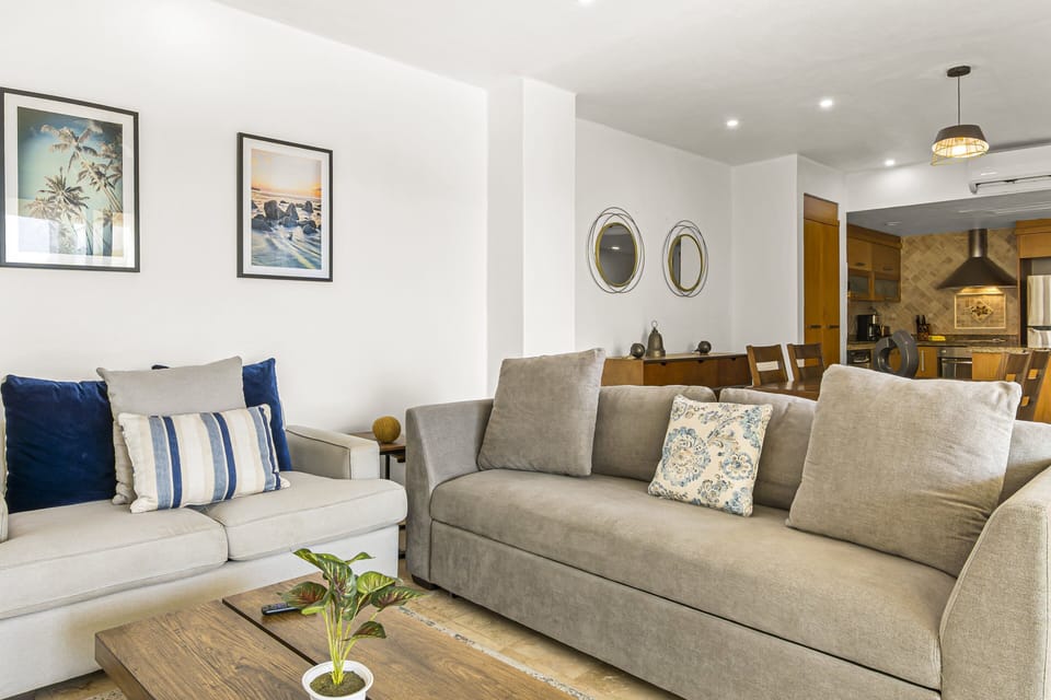 Relax in the stylish living area with plush seating, Smart TV, natural light, and direct access to the private balcony with tropical views.