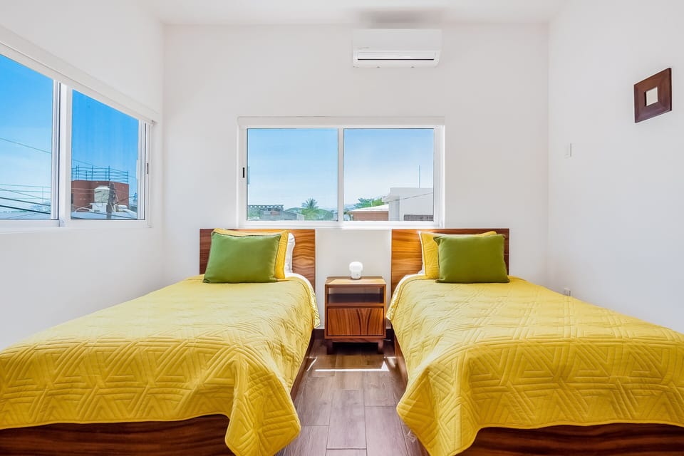 A comfortable bedroom with two cozy twin beds, air conditioning, and plenty of natural light—ideal for friends, kids, or additional guests.