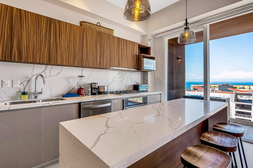 Modern kitchen with sleek finishes, stainless steel appliances, and a spacious breakfast bar. Opens to a private balcony with beautiful ocean views—perfect for cooking and dining with a view.