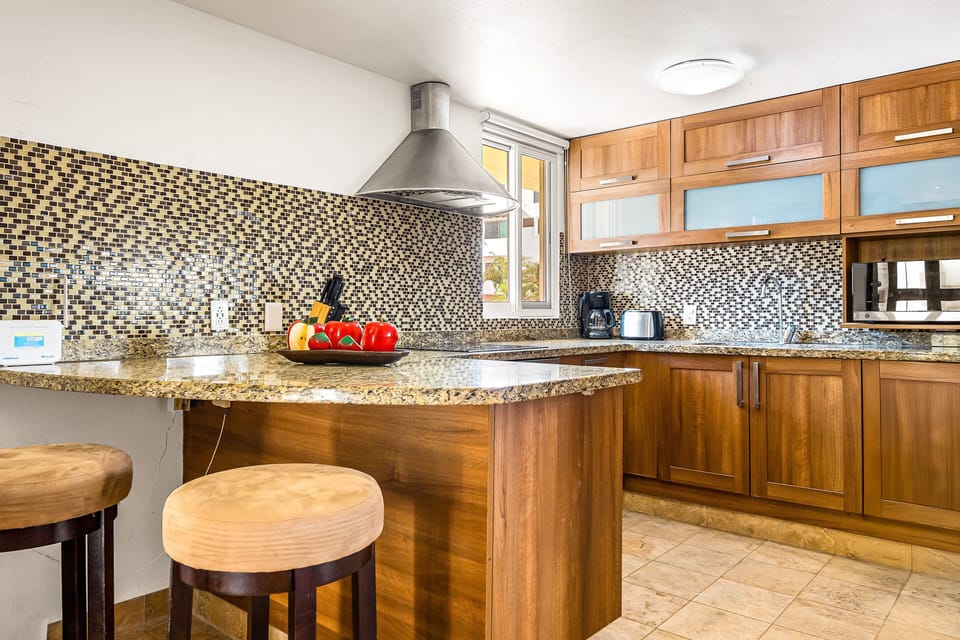 Cook with ease in a fully equipped kitchen featuring granite countertops, custom wood cabinetry, bar seating, and premium appliances.