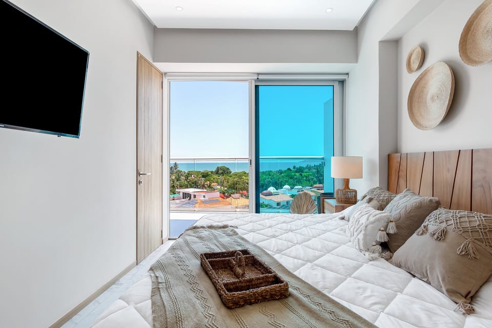 Wake up to natural light and ocean views from this cozy bedroom, complete with a plush bed, calming décor, and direct access to the private terrace.