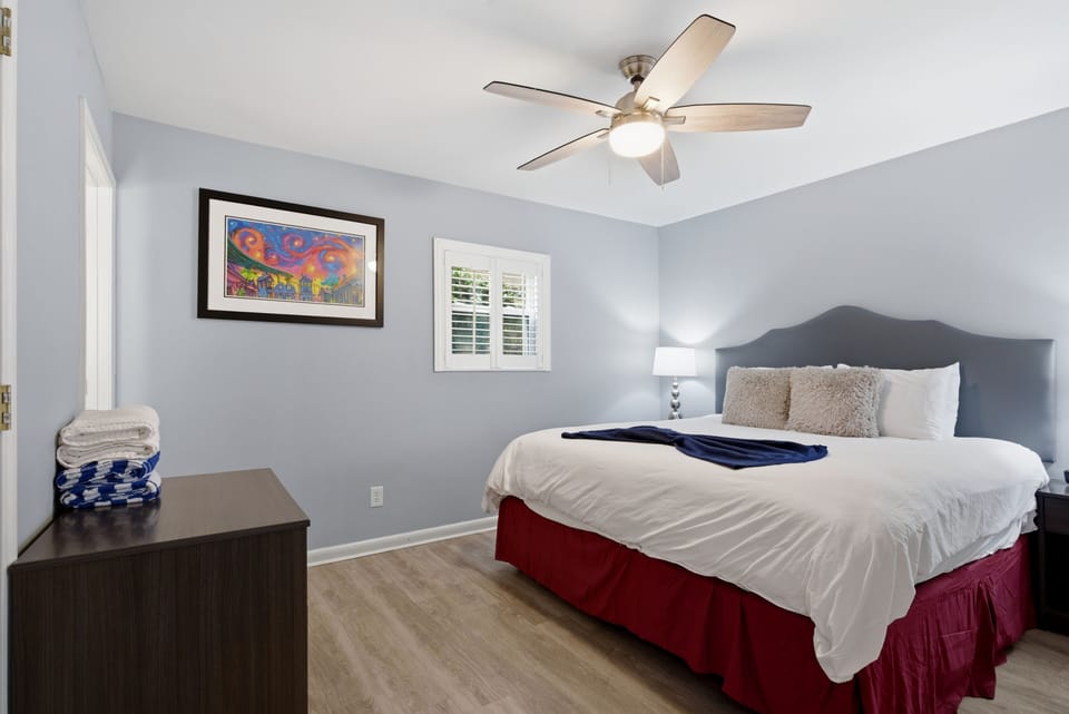 Cheerful bedroom w/ framed art & warm natural light streaming in.
