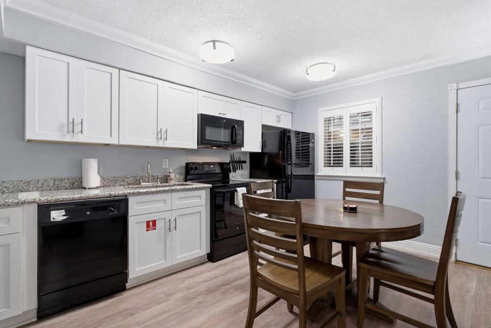 Compact kitchen w/ black appliances & white cabinetry — everything you need.
