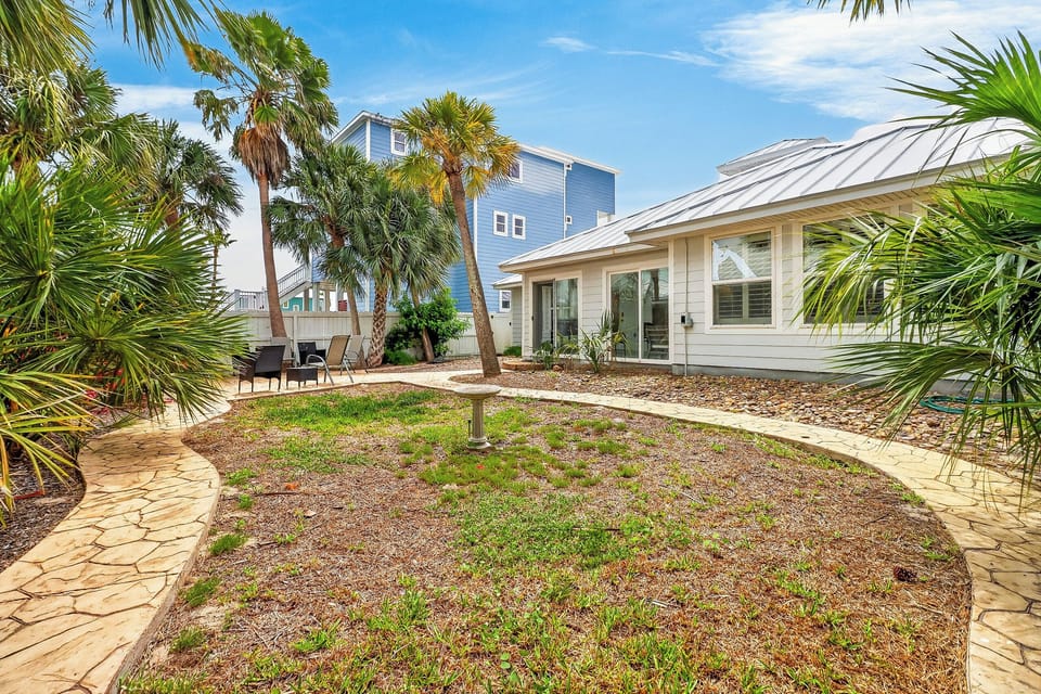 Beautiful coastal property with tropical landscaping, palm trees, and outdoor seating areas perfect for your beach getaway.