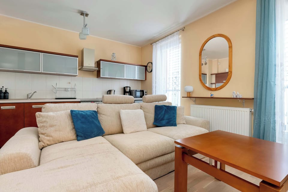 This wide-angle shot captures the seamless flow between the lounge area and the kitchen space. The warm wall colors and natural light from the windows make the interior feel inviting and spacious.