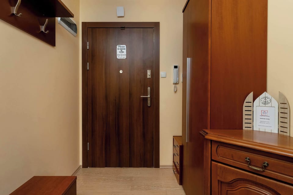 The entrance hallway contains a sturdy dark wood door and a matching wooden dresser for storage. A wall-mounted coat rack provides a practical solution for guests' outerwear upon arrival.