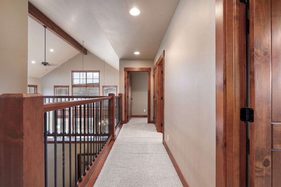 Warm wood accents and soft carpeting create a welcoming upstairs hallway where you'll find comfortable bedrooms just steps away.