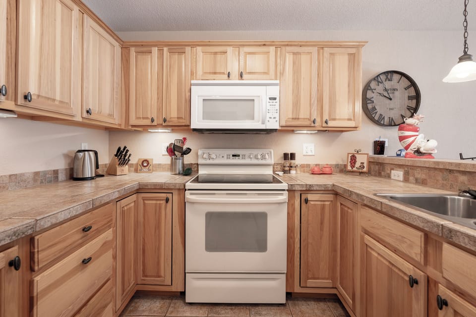 Your fully-equipped kitchen awaits with warm wood cabinets, granite counters, and everything you need to create memorable meals during your stay.