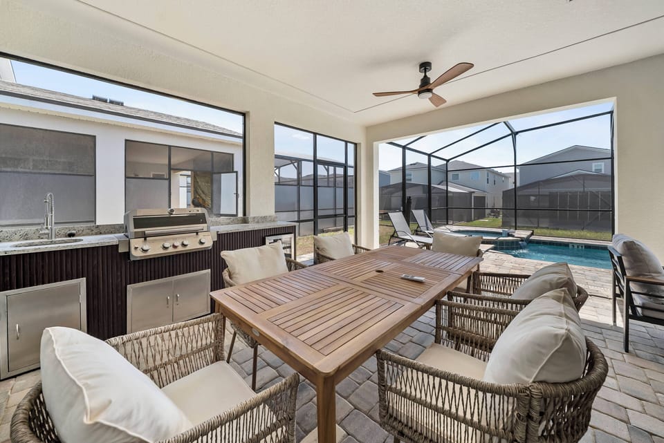 Dine al fresco on the stylish screened-in patio, where a sturdy wooden table and comfy wicker chairs await. A built-in grill is perfect for your meals, and the inviting pool sparkles just beyond the large windows.