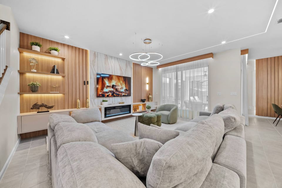 Unwind in the cozy living room with plush gray sofas and modern lighting that highlights natural wood accents and a stylish entertainment unit, creating a welcoming atmosphere perfect for gathering with friends and family.