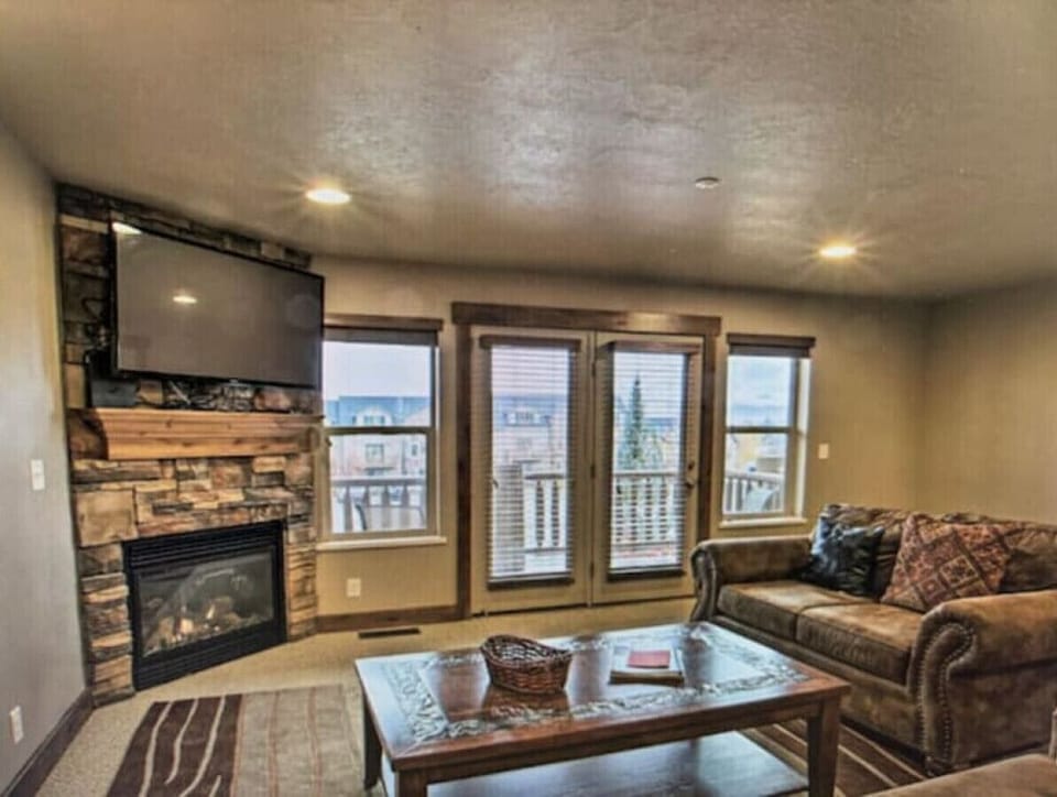 Living Room | Stone Fireplace | Balcony Access & Mountain Views