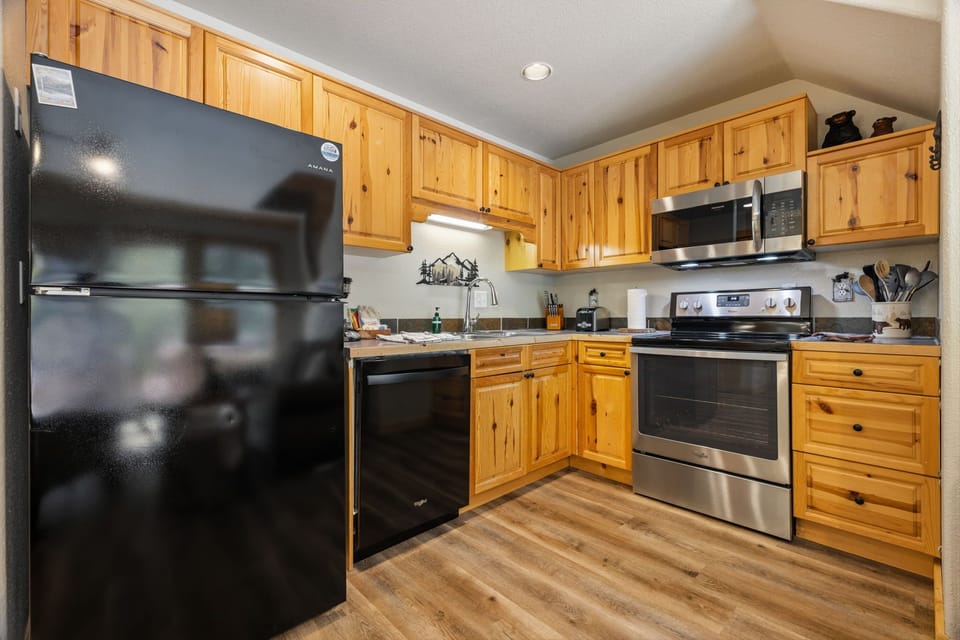 Your fully equipped kitchen features warm wood cabinets and modern stainless steel appliances, ready for creating memorable meals during your mountain getaway.