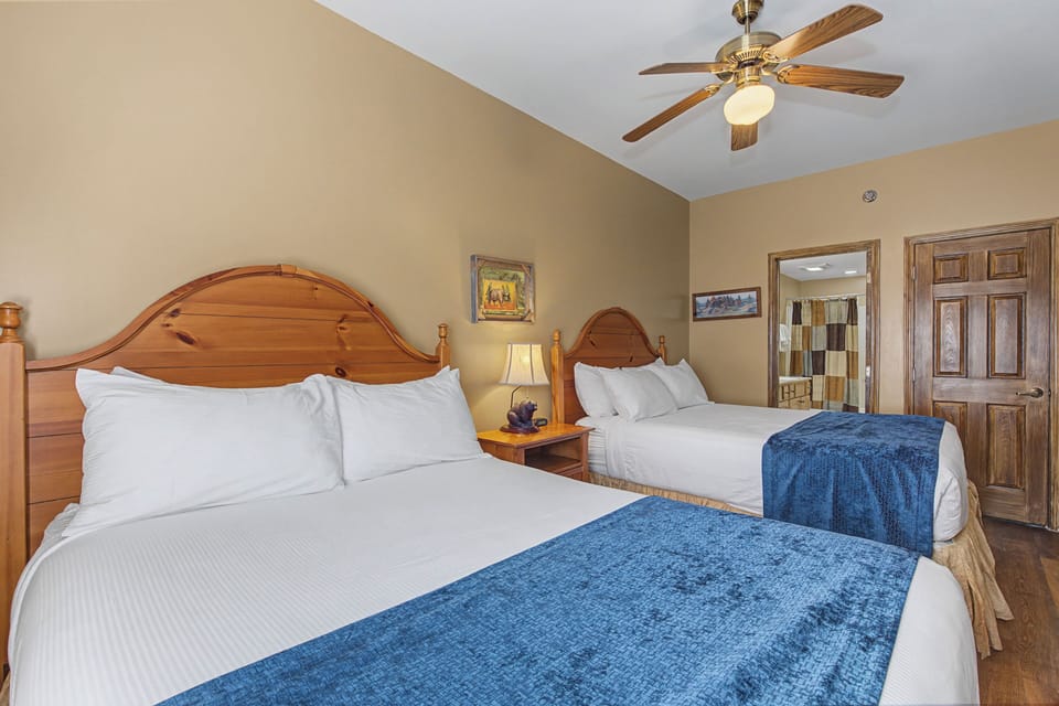 Unwind in your spacious bedroom with two plush beds, warm wood furnishings, and a gentle ceiling fan keeping you comfortable all night.