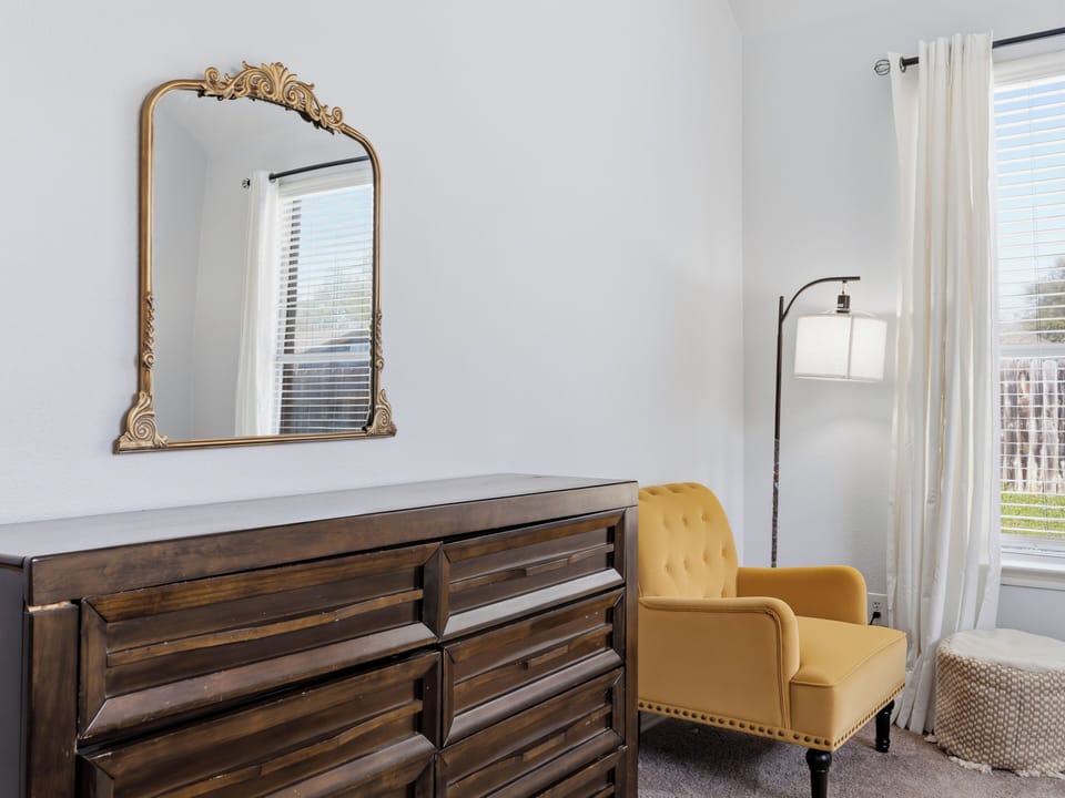 Cozy up in your stylish reading nook with a plush mustard chair and elegant furnishings that make this space feel like home.