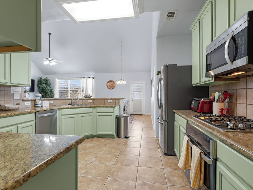 Your spacious culinary haven features granite counters, full-size appliances, and charming sage cabinets perfect for preparing memorable meals during your stay.