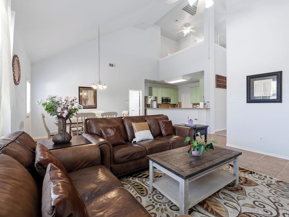 Sink into rich leather seating in this bright open-concept living space, where soaring ceilings and natural light create your perfect relaxation haven.