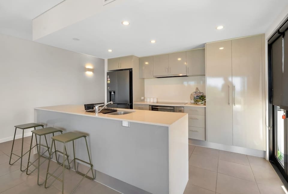 A sleek central island with seating invites casual meals, morning coffee, or a relaxed place to gather while cooking.