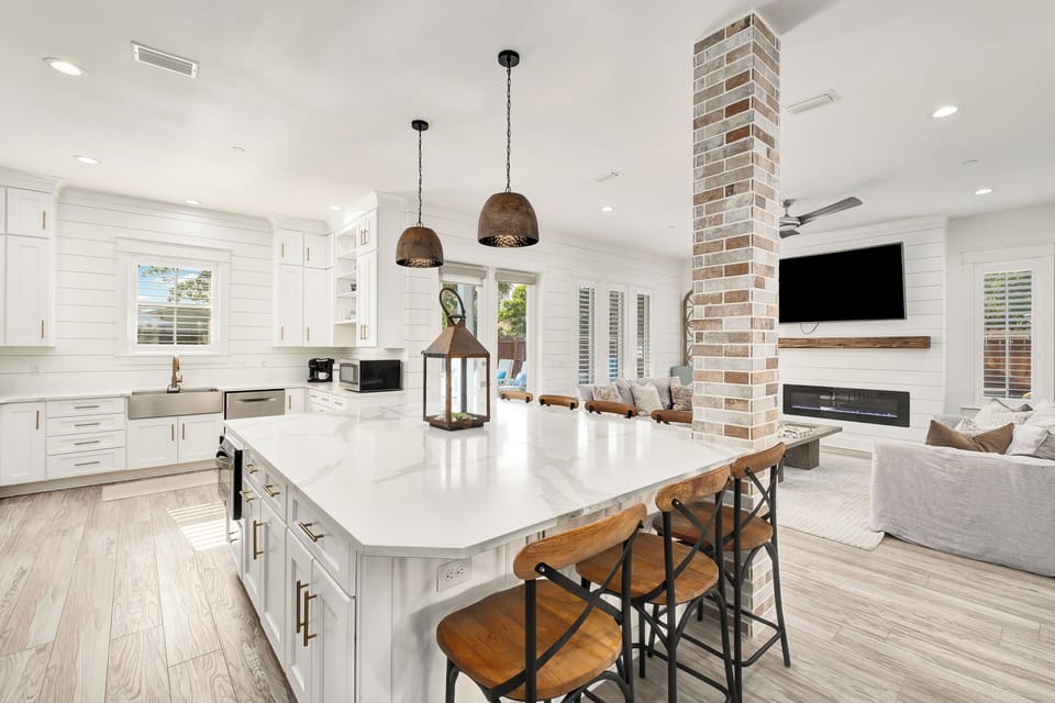 Your open-plan haven blends a gourmet kitchen with a cozy living area, complete with a modern fireplace and inviting seating—perfect for gathering, cooking, or unwinding together.