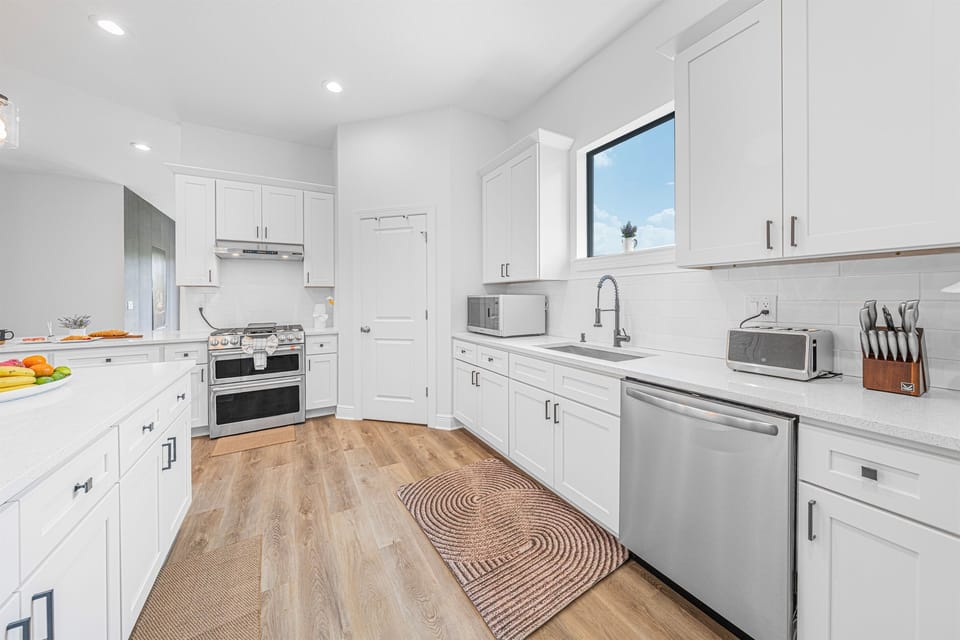 Fully equipped kitchen featuring sleek white cabinetry, modern appliances, and plenty of prep space.