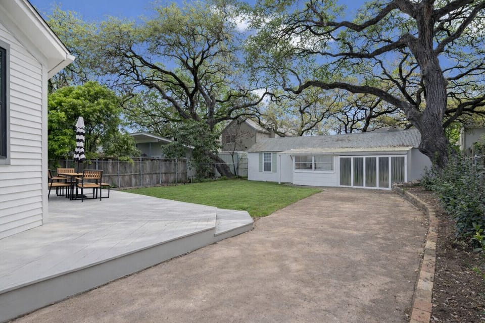 A spacious backyard with a large lawn, patio seating, and plenty of room to enjoy the outdoors.
