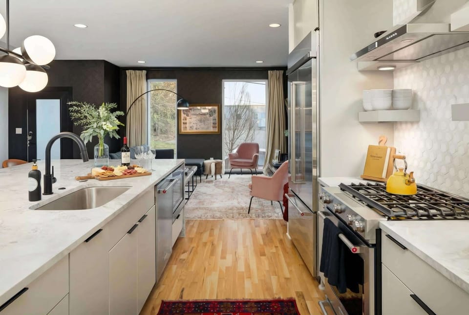 Kitchen island with gas stove opens directly to the living room on hardwood floors. No one gets stuck cooking while everyone else watches the TV