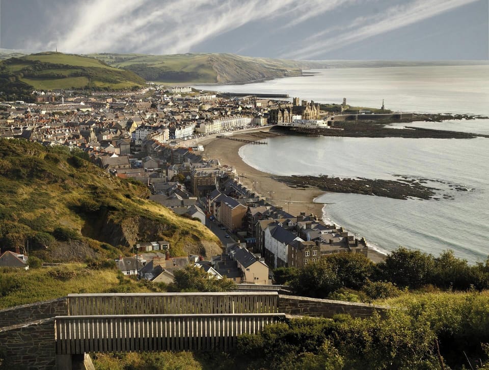 Coastal town with curved bay and sandy beach viewed from a hillside