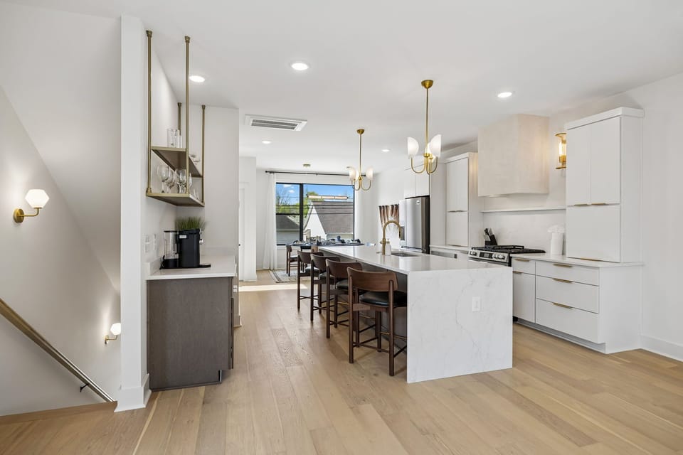 Kitchen: A spacious kitchen featuring a large island, bar stools, and pendant lights above.