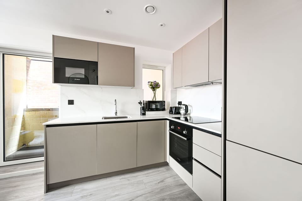 Fitted kitchen with a full-size oven, hob, microwave and sink, patio door alongside