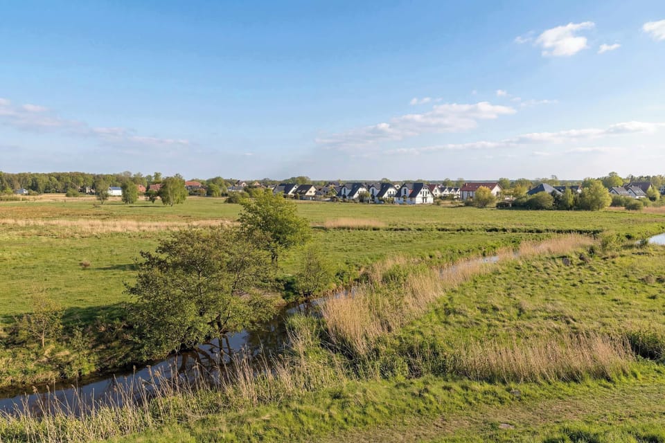 A panoramic view from the property overlooks lush green fields and distant houses, suggesting a quiet, suburban location.