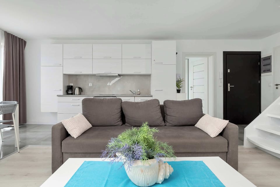 The open-plan living area combines a comfortable lounging space with a dining table and a functional white kitchenette.