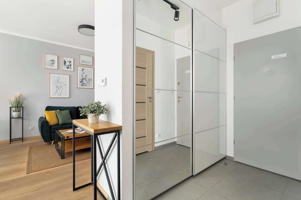 A hallway and storage area features large mirrored wardrobes that reflect the living space and help open up the interior.